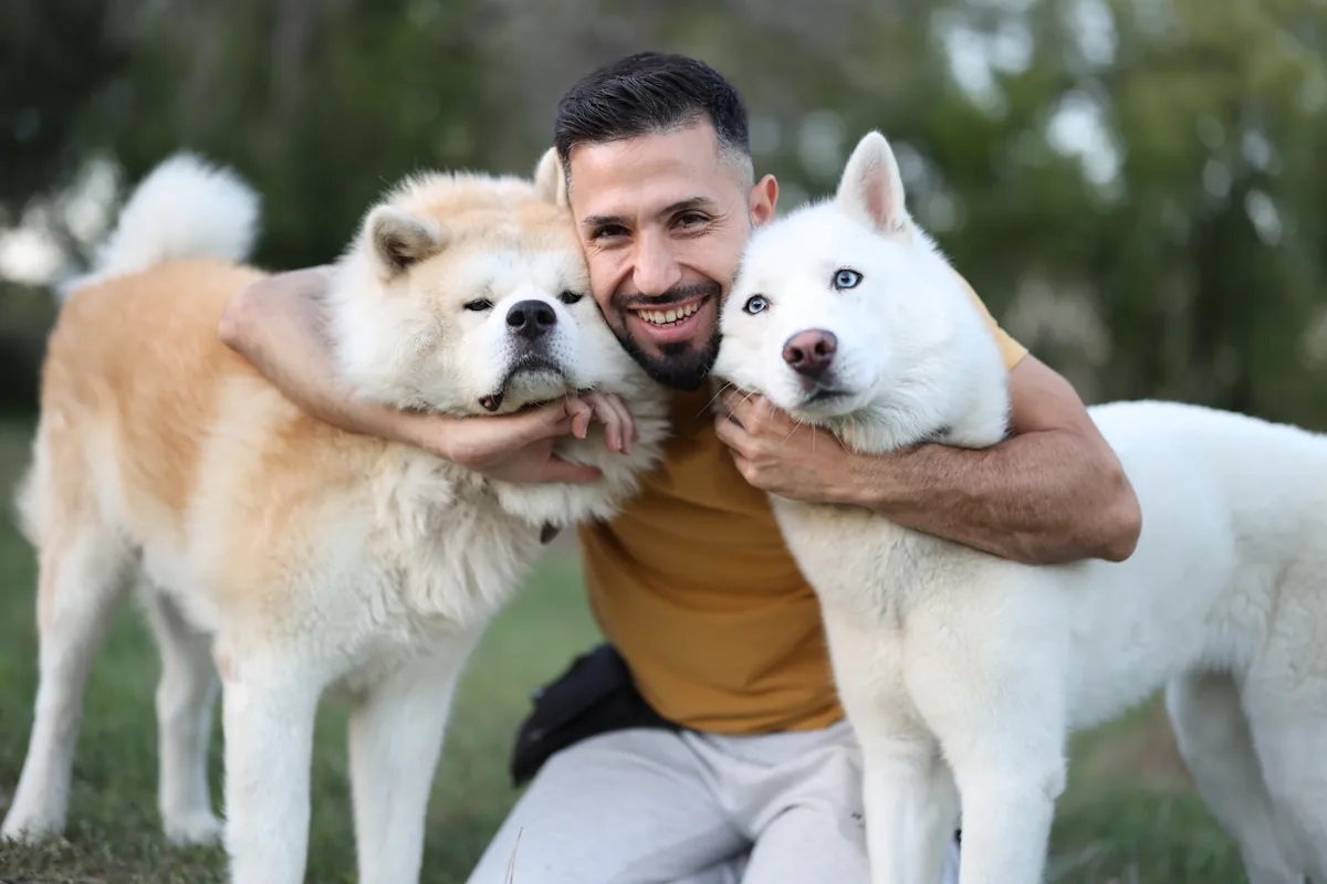 Un homme qui tient deux chiens contre lui